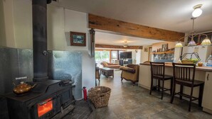 A cozy living room with a fireplace, a dining area with a bar, and a kitchen with stone countertops. - Beautiful All Season Cottage on Remi Lake (Moonbeam)