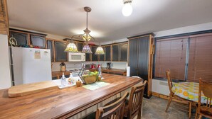 A kitchen with wooden cabinets, a microwave, a stove, and a dining area with a wooden table and chairs. - Beautiful All Season Cottage on Remi Lake (Moonbeam)