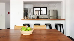 Una cocina moderna con salpicadero de ladrillo blanco, encimera de madera y una zona de comedor con mesa y sillas de madera.