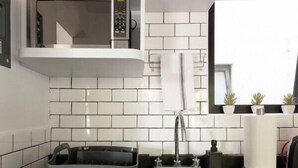 Una cocina moderna con armarios blancos, un lavamanos de acero inoxidable, un microondas y una encimera negra.