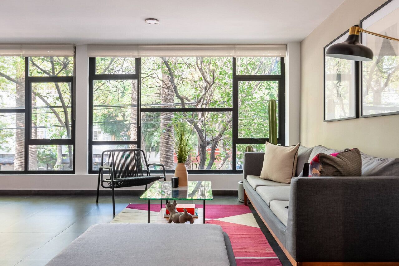 A modern living room with large windows, a sofa, a coffee table, and a chair.