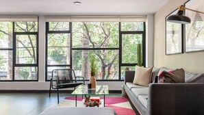 Una sala de estar moderna con ventanas amplias, un sofá, una mesa de centro y una silla.
