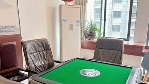 A room with a green pool table, leather chairs, a potted plant, and a window with a city view. - Aishang Yihao Apartment (Zhangjiajie)