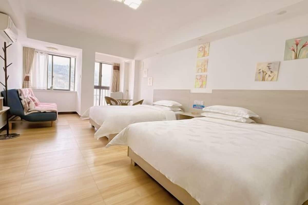 A hotel room with two beds, a desk, a chair, and a window with curtains.