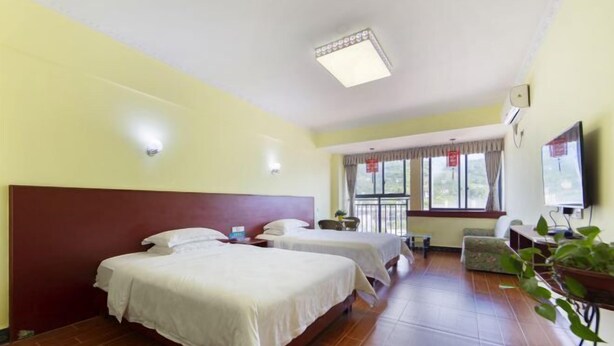 A hotel room with two beds, a TV, a desk, and a window with curtains. - Aishang Yihao Apartment (Zhangjiajie)