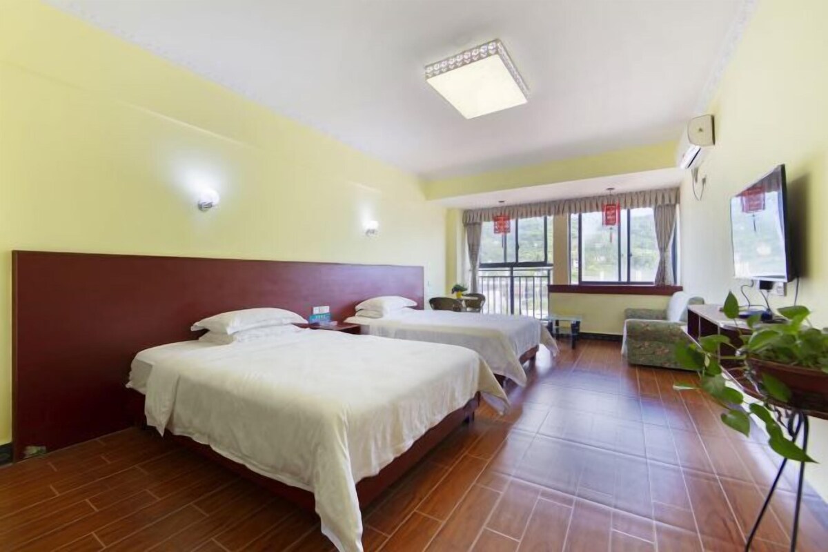 A hotel room with two beds, a TV, a desk, and a window with curtains.