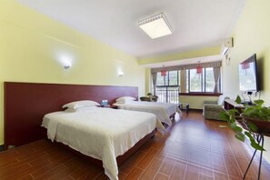 Une chambre d’hôtel avec deux lits, une télévision, un bureau et une fenêtre avec des rideaux.