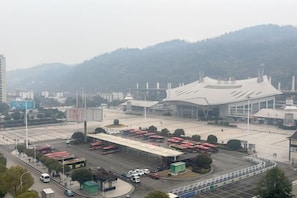 A large industrial building with a curved roof, surrounded by a parking lot with multiple vehicles. - Aishang Yihao Apartment (Zhangjiajie)