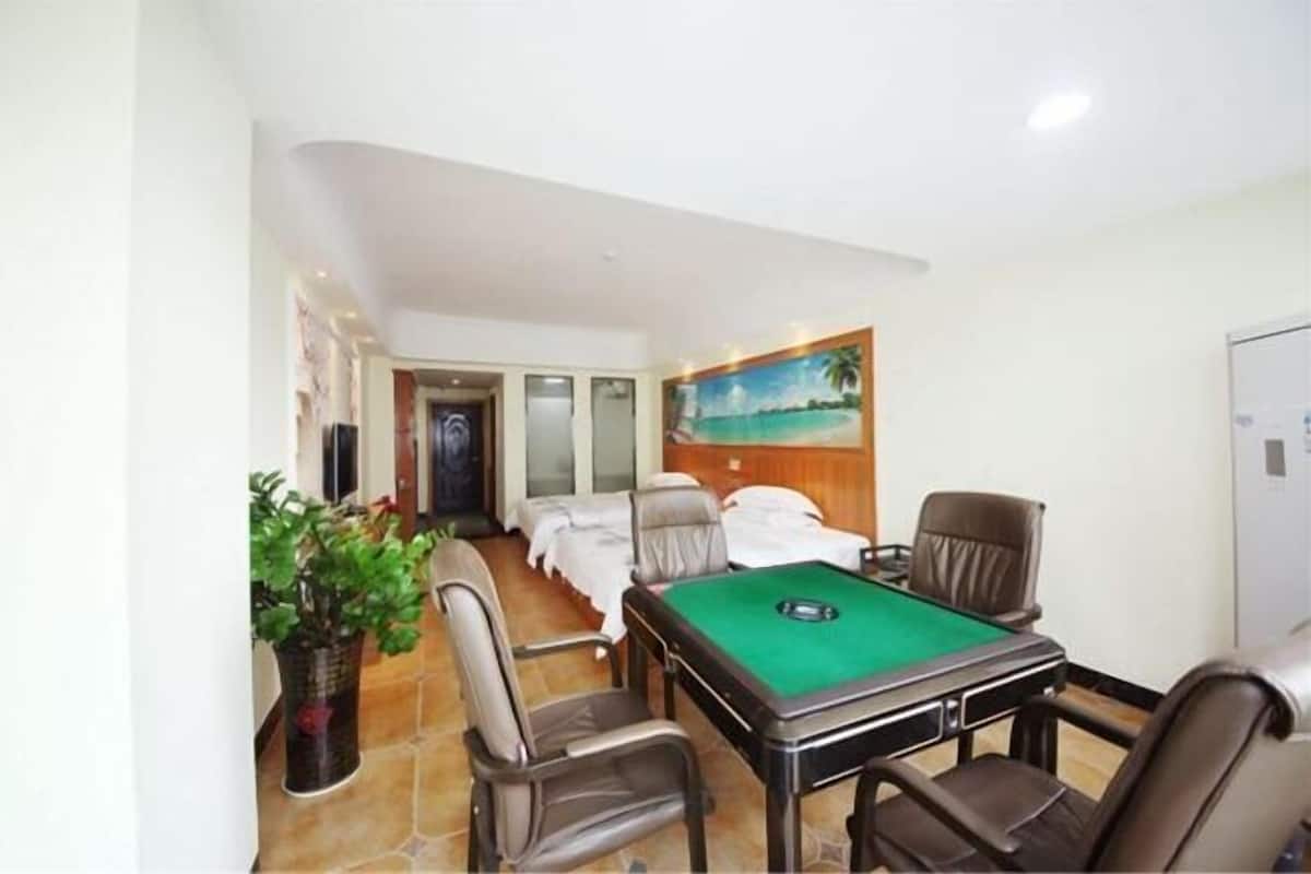 A room with a pool table, two chairs, a bed, and a painting of a beach scene.