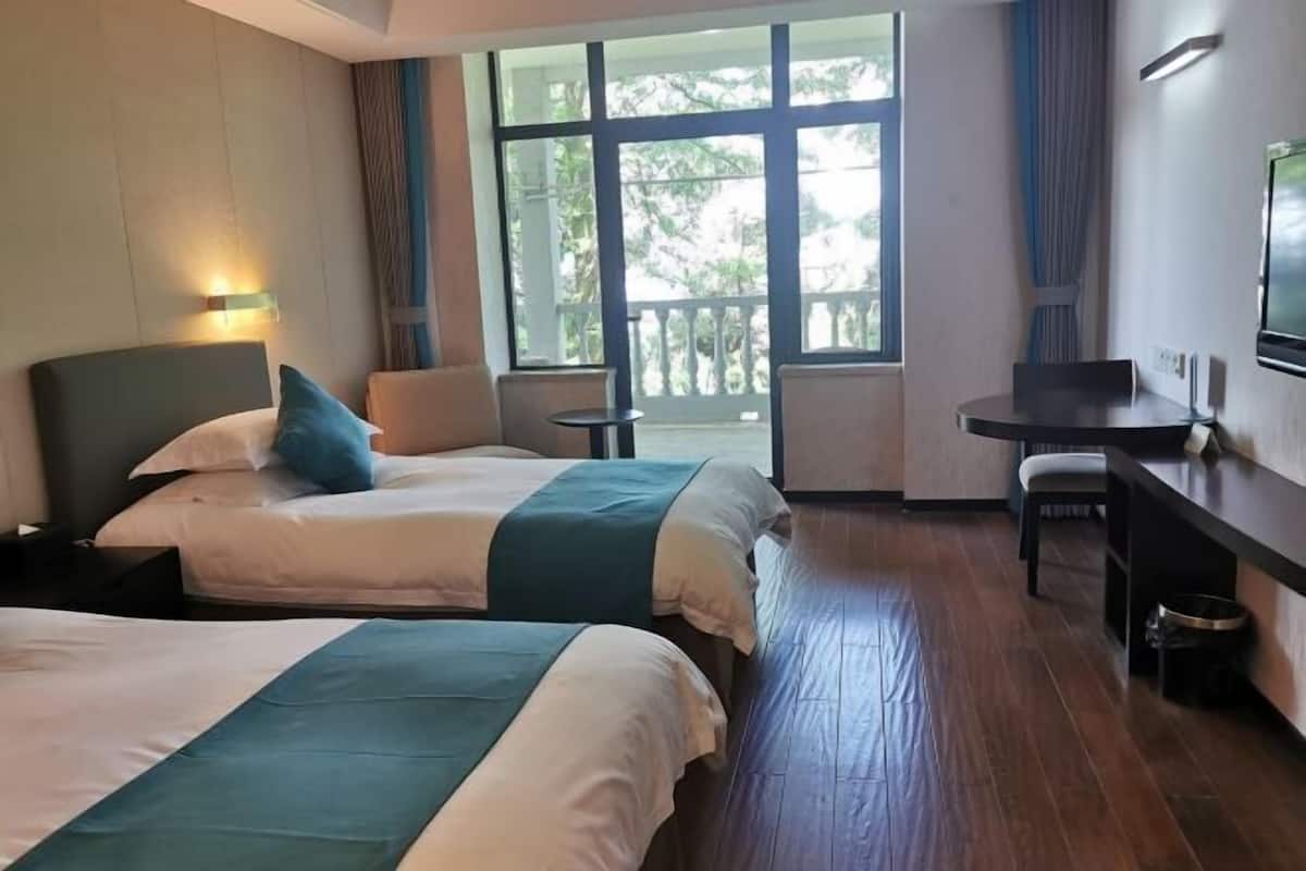 Une chambre d’hôtel avec deux lits, un bureau, une chaise et un balcon avec vue.