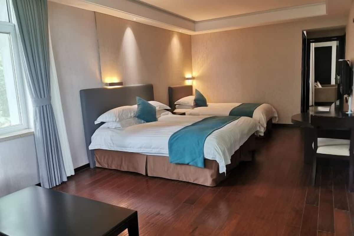 Une chambre d’hôtel avec deux lits, un bureau et un miroir.