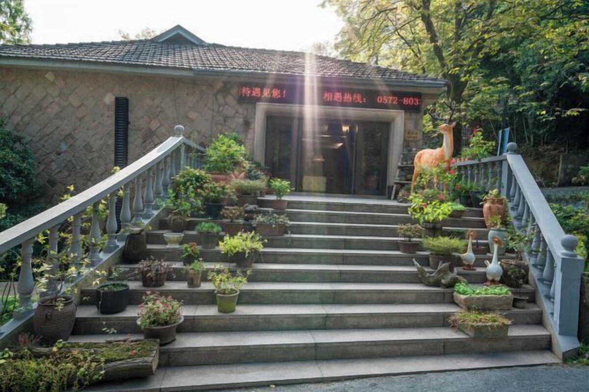A stone building with a tiled roof, a staircase with potted plants, and a llama statue.