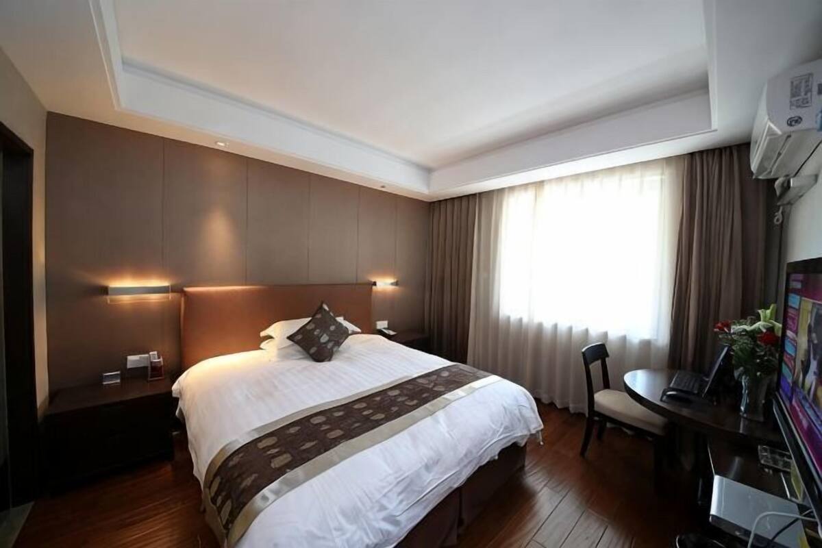 Une chambre d’hôtel avec un grand lit, des tables de chevet, un bureau et une chaise.