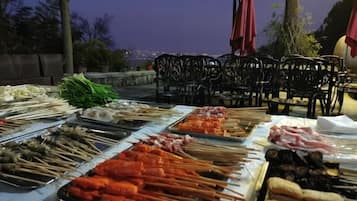 An outdoor food market with various food items displayed on trays.