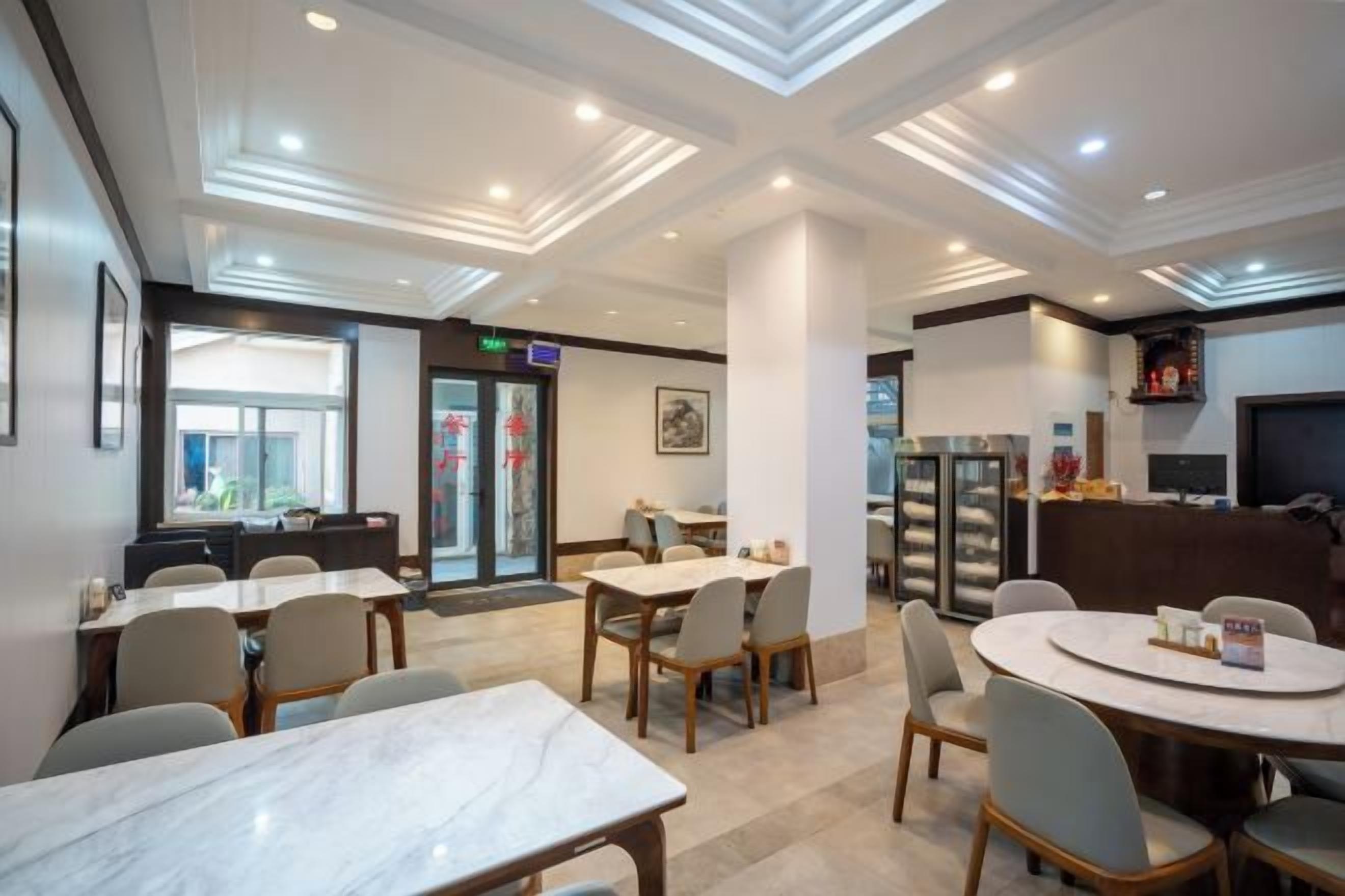 A hotel dining area with marble tables, chairs, and a refrigerator.