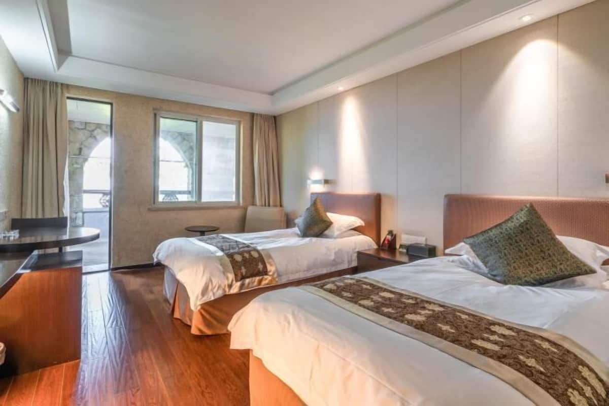 Une chambre d’hôtel avec deux lits, un bureau et une vue sur l’extérieur.