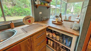A kitchen with wooden cabinets, a sink, and a window overlooking greenery.