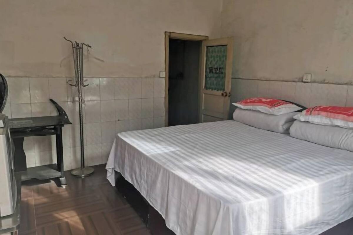 Een kamer met een bed, een bureau en een kapstok.