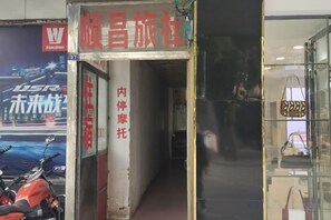 Un escaparate con un letrero en idioma extranjero, una motocicleta estacionada afuera y una exhibición de bolsos en el interior.
