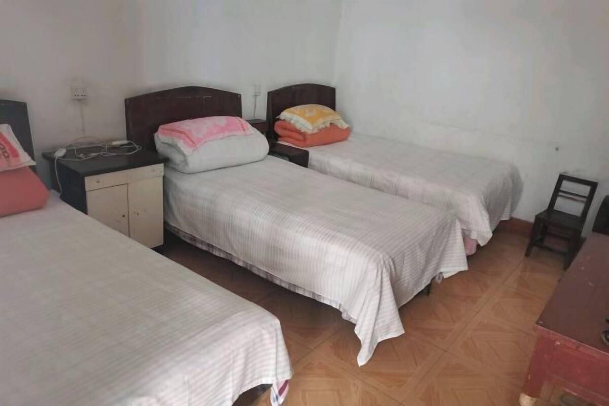 Een kamer met twee enkele bedden, een klein bureau, een stoel en een kledingkast.