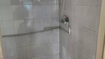 A tiled shower area with a hose and a faucet.