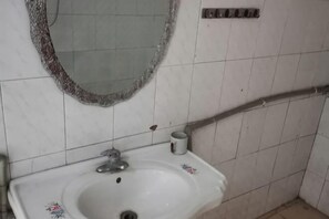 Une salle de bain avec un lavabo blanc, un miroir et un porte-serviettes.