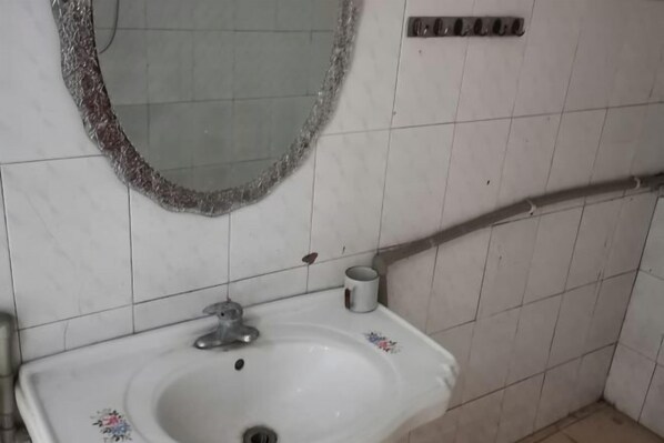 Une salle de bain avec un lavabo blanc, un miroir et un porte-serviettes.