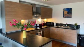 A modern kitchen with wooden cabinets, a black countertop, and a stainless steel range hood.