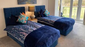 A bedroom with two beds, a night sky painting, and a large window.
