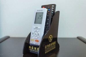 A digital clock with a remote control on a stand. - Tengjia Hotel (Tengchong)