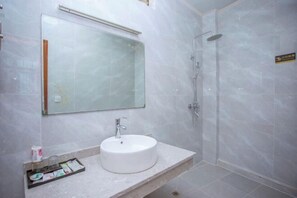 A bathroom with a white sink, a mirror, and a shower. - Tengjia Hotel (Tengchong)