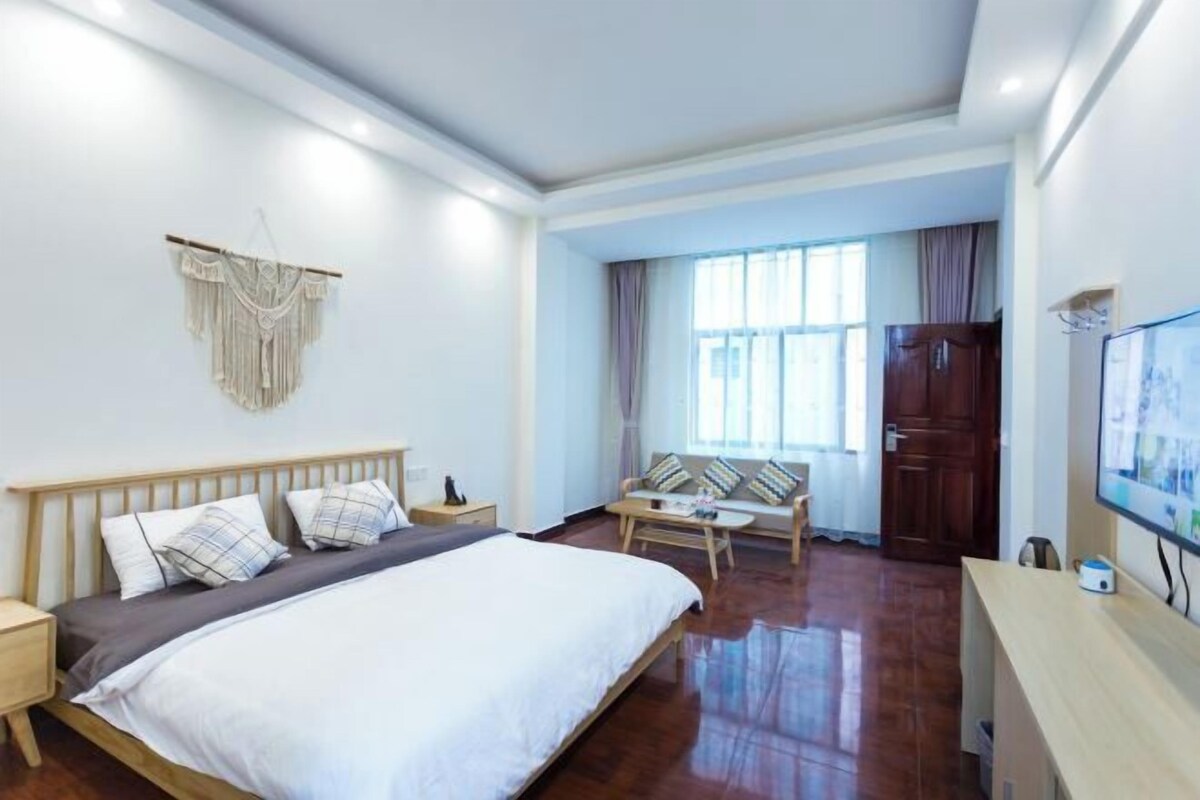 A bedroom with a bed, bedside table, TV, and a seating area with a table and chairs.