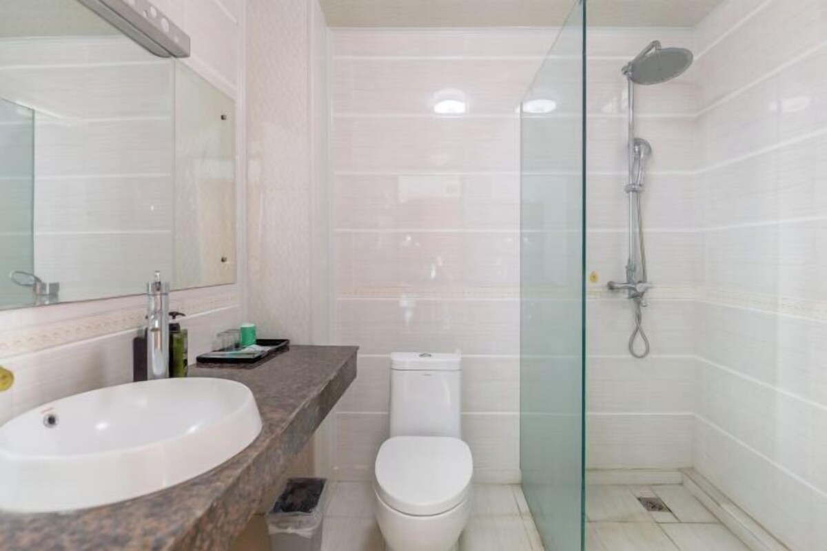 A bathroom with a white sink, toilet, and glass-enclosed shower area.