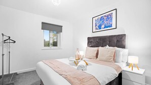 Una camera da letto moderna con un letto grande, un comodino con una lampada, una finestra con vista e un appendiabiti.