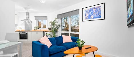 Een moderne woonkamer met een blauwe bank, een salontafel en een kleurrijk vloerkleed.