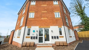 Un edificio residenziale a più piani con facciata in mattoni, finestre con cornice bianca e un ingresso centrale con porta in vetro.