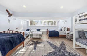 A room with bunk beds, a starfish rug, and wall art of birds.