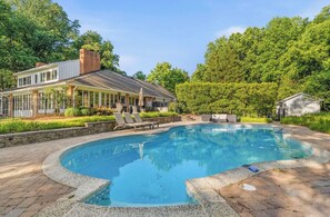 A swimming pool with a curved edge, surrounded by a paved deck.