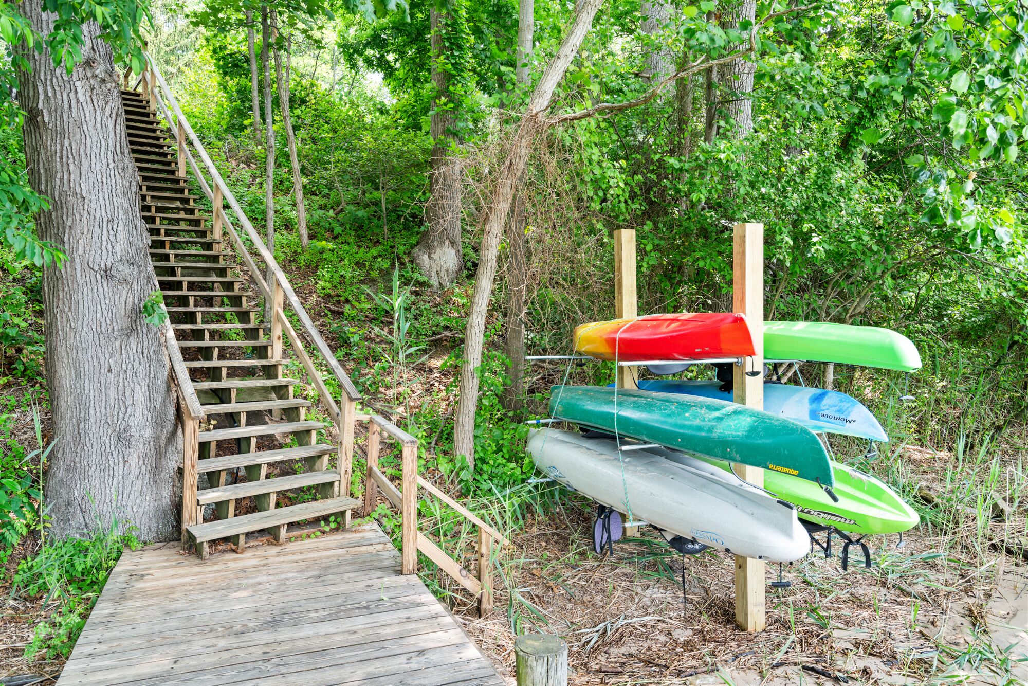 A wooden staircase leading up to a platform with canoes and kayaks.