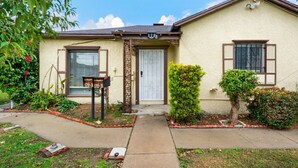 Una casa de un piso con fachada color beige, puerta delantera blanca y buzón.