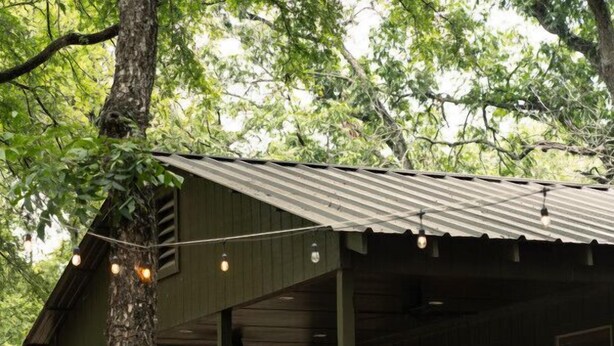 Un rustico chalet con veranda in legno, tavolo da picnic e zona barbecue.