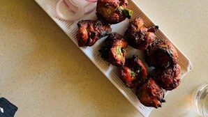 A plate of tandoori chicken with sliced onions and lime on a table. - Assam Lodge (Guwahati)