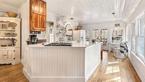 Une cuisine spacieuse avec des meubles blancs, un îlot central et des éléments décoratifs en bois.