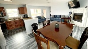 A spacious living area with a wooden dining table, a sofa, and a TV mounted on the wall. - Sarasota Home Away From Home (Sarasota)