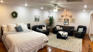 Uma sala de estar espaçosa com uma cama grande, dois sofás, uma mesa de centro e um ventilador de teto.