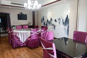 Un área de comedor con una mesa redonda, sillas y un mural en la pared.