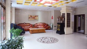 A lobby with a central seating area, a large decorative ceiling, and a framed artwork on the wall.