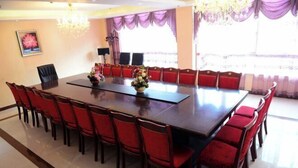 A conference room with a large rectangular table surrounded by red chairs, a chandelier, and a window with purple curtains. - Yaxuan Hotel (Pingli)