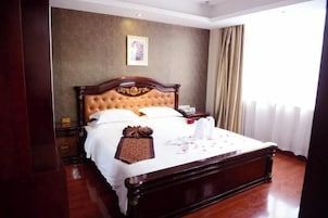 Una cama grande y ornamentada con estructura de madera y cabecero acolchado, una mesita de noche y un cuadro enmarcado en la pared.