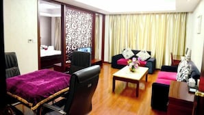 A hotel room with a bed, a desk, a sofa, and a dining table. - Yaxuan Hotel (Pingli)